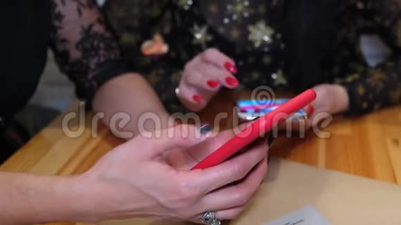 两个年轻女孩在咖啡馆里使用智能手机无线上网手握设备特写视频的预览图