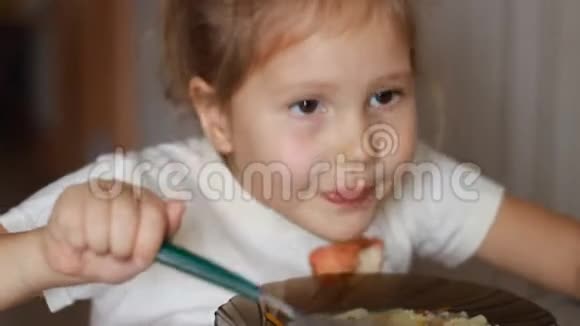 孩子吃汤把坐在家里做饭和吃食物的桌子上的女婴关上视频的预览图