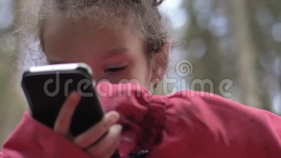 5岁的小女孩在美丽的大自然中站在瀑布前用智能手机视频的预览图