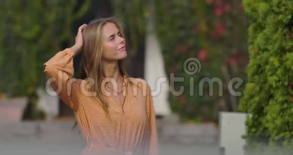 漂亮的白人女人穿着芥末衣服用手摸着她的头微笑着可爱的女孩站在视频的预览图