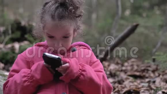 可爱的年轻快乐的五岁小女孩在美丽的大自然中使用智能手机视频的预览图