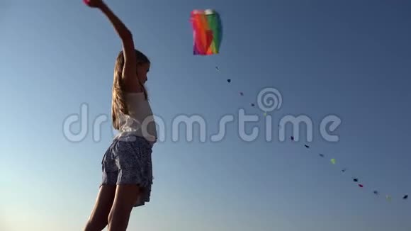 日落时沙滩上玩飞风筝的孩子海岸上的快乐小女孩视频的预览图