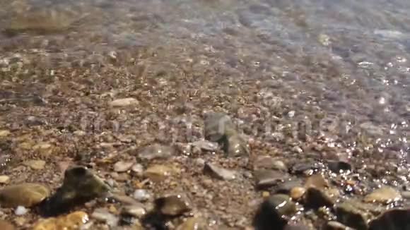 超慢的水波在岸上洗涤闪闪发亮的湿卵石视频的预览图