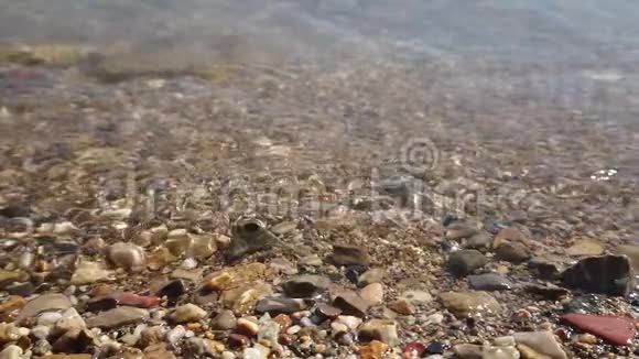 在海滩特写镜头上超级慢的波浪溅到鹅卵石上视频的预览图