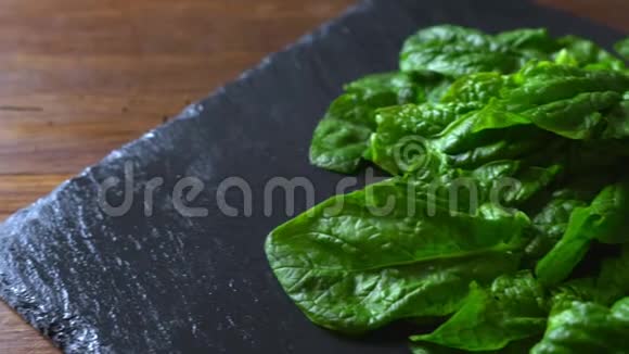 健康素食理念将新鲜采摘的绿色菠菜叶放在石板和木桌上的特写背光视频的预览图