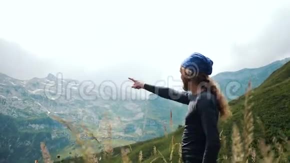 留着长发的徒步旅行者用手指着山峰登山者欣赏美丽的风景视频的预览图