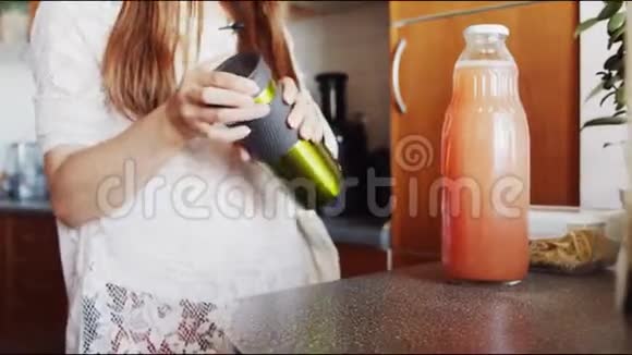 女孩把苹果汁倒进厨房的桌子上的热水瓶里视频的预览图