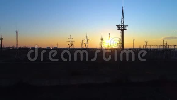 输电塔的鸟瞰图橙色日落背景下带有电力线的输电塔的轮廓图视频的预览图