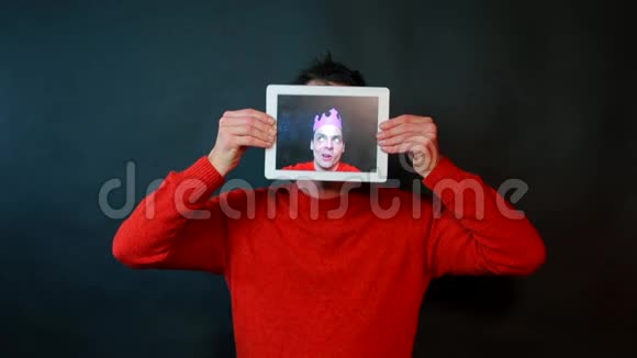 平板电脑屏幕上一个人的肖像男人鬼脸环顾四周视频的预览图