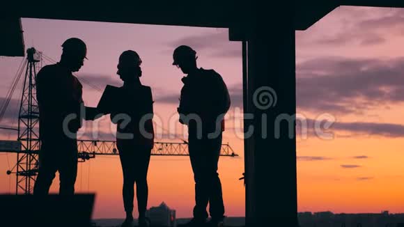 三名工程师在日落背景下在一个建筑工地工作现代施工现场的施工工人视频的预览图