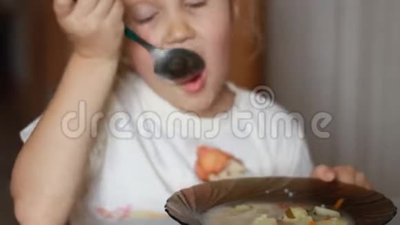 孩子吃汤特写一个小女孩坐在家里做饭和吃食物的桌子上的肖像视频的预览图