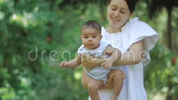 母亲带着她刚出生的女儿在公园的一片绿草上快乐的年轻母亲和孩子享受大自然视频的预览图