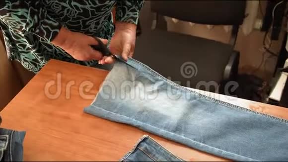 高级裁缝用木桌剪旧牛仔裤视频的预览图