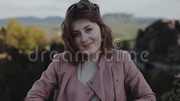 在模糊的山景面前一位美丽的微笑的年轻女子的近距离肖像观慢动作视频的预览图
