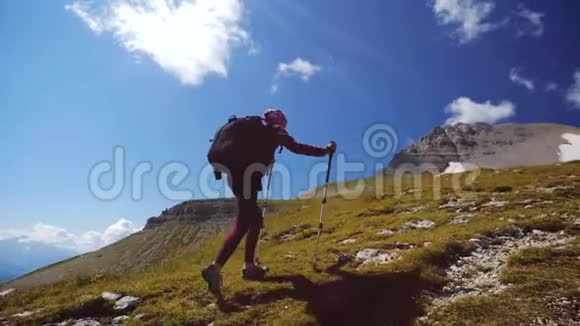 一名年轻女子背着背包和徒步行走的两根杆子上山朝山顶走去慢动作夫人视频的预览图