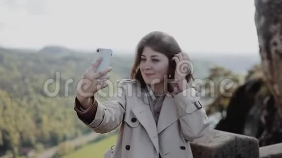 近距离观看年轻漂亮的微笑女孩自拍与山的背景焦点从女孩转移到视频的预览图