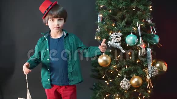 一个戴着红帽子的孩子站在圣诞树附近视频的预览图