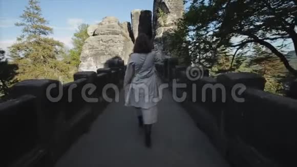 慢动作后景美丽的微笑年轻女孩走在山上的岩石小径上自拍视频的预览图