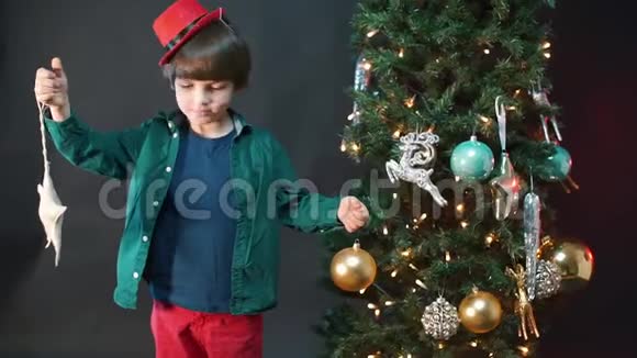 这个男孩手里拿着新年树附近的圣诞玩具视频的预览图