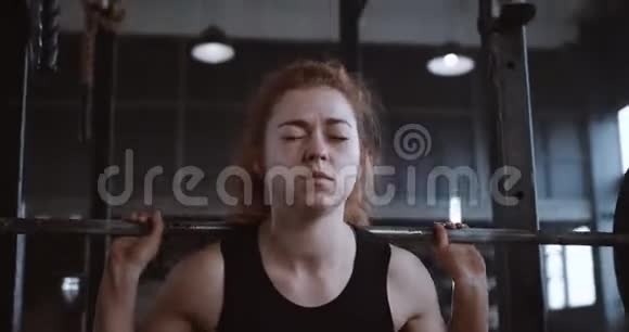 年轻漂亮的红头发运动女子在大型专业健身房缓慢运动中用力举起沉重的杠铃视频的预览图