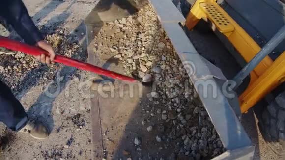 工人们从平地机桶里取石头然后把石头放进坑里视频的预览图