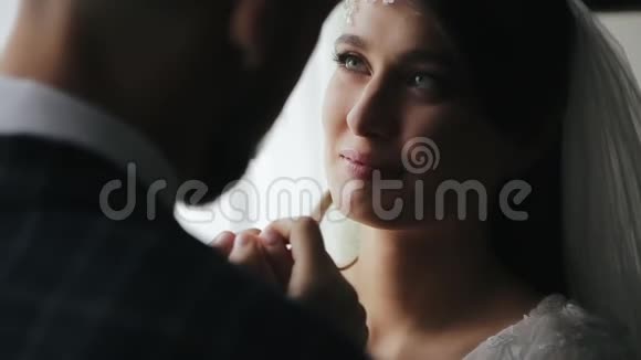 新婚夫妇牵着手在窗前举行新郎新娘仪式穿着白色裙子的女孩视频的预览图