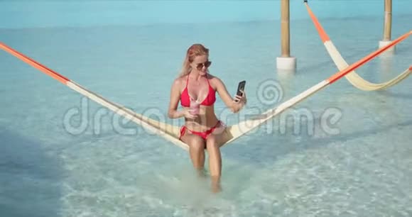 有鸡尾酒的快乐女人在吊床上自拍视频的预览图