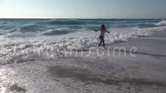 儿童在海滩玩耍观看海浪女孩在夏天的海岸线上奔跑视频的预览图