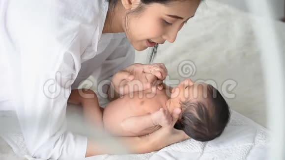 母亲在白色的床上与刚出生的婴儿交谈柔和的日光如爱的情感细心和温暖视频的预览图