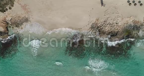 绿松石水晶般清澈的海浪在海滩和岩石上破碎视频的预览图