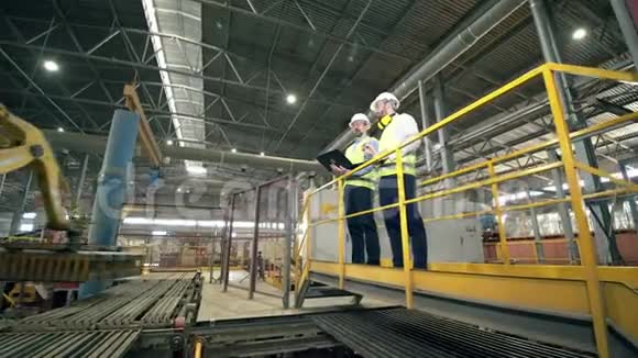 两名技术人员在现代工厂检查机械臂视频的预览图