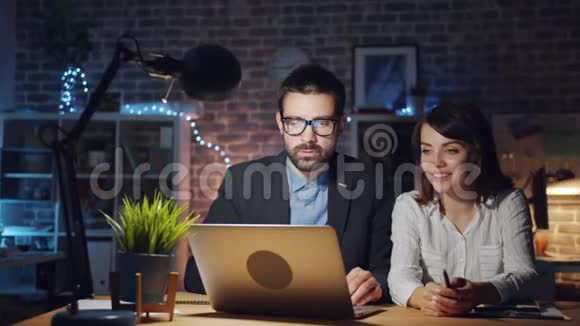 快乐的上班族在工作场所晚上用手提电脑大笑视频的预览图