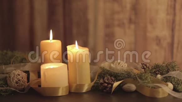 圣诞节的背景是三支点燃的蜡烛松枝天然松果金色缎子和白色有机带的火焰视频的预览图