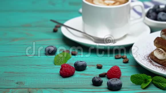 用覆盆子和蓝莓配成的提拉米苏甜点部分和木制背景的咖啡视频的预览图