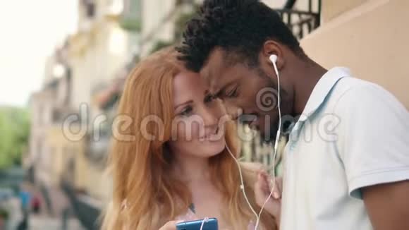 一对年轻夫妇在街上用耳机听音乐视频的预览图