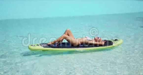在享受暑假的桨板上放松的女人视频的预览图