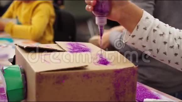 女孩倒出紫色的闪光在纸板箱上做字母视频的预览图