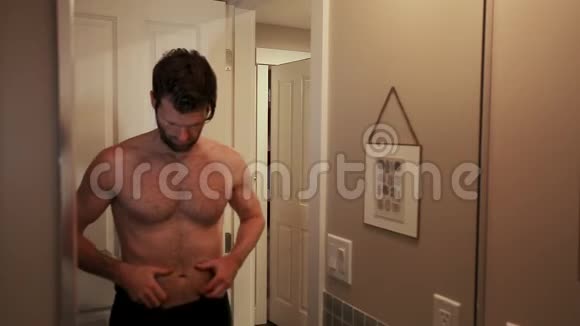 英俊的白种人年轻男子看着自己在浴室的镜子同时检查他的腹部脂肪HD24FPS视频的预览图