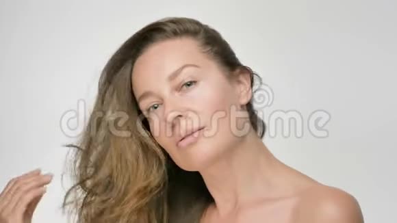 年轻女性皮肤光滑健康的特写美女肖像她用手轻轻抚摸头发玩味十足视频的预览图