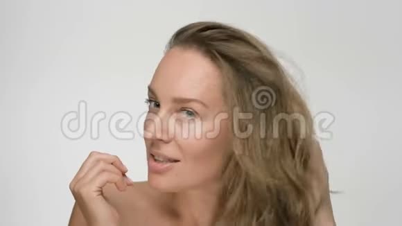 年轻女性皮肤光滑健康的特写美女肖像她用手轻轻抚摸头发玩味十足视频的预览图