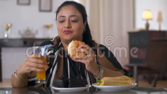 印度超重妇女在家吃汉堡垃圾食品和不健康食品视频的预览图