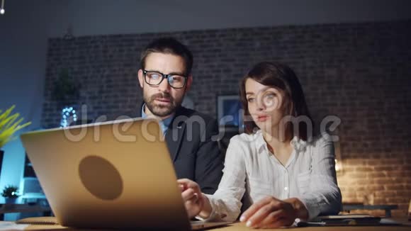 专业人士看着笔记本电脑屏幕晚上在办公室聊天视频的预览图