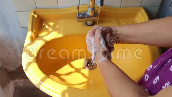白天用肥皂在黄色洗手盆附近洗手突出拇指区域以防止病毒和视频的预览图