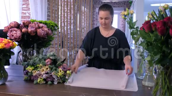 花商妇女在花店用白纸包装大花束视频的预览图