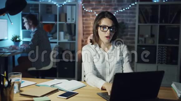 在办公室工作的人在夜间协助漂亮女孩做电脑工作时动作缓慢视频的预览图