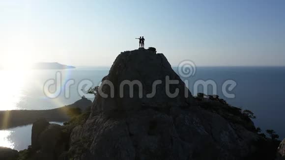 日出时一对年轻的恋人站在山顶上挥舞着双手视频的预览图