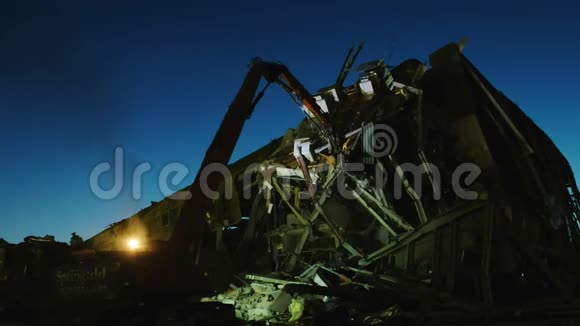 挖掘机在夜间拆卸危险的冰球场视频的预览图