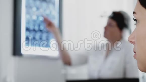 医生给诊断疾病的女病人展示x光图像并解释治愈方法视频的预览图