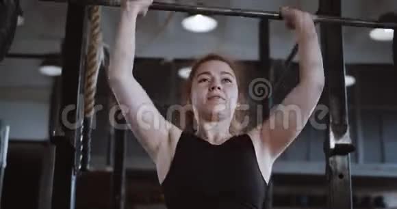特写年轻漂亮的红头发运动女子举起沉重的横杆在大型专业健身房进行极限锻炼视频的预览图