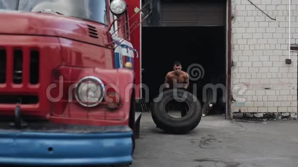 英俊的年轻人拿着轮胎在消防车旁边蹲着视频的预览图